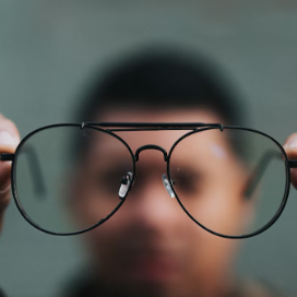 blurred vision of a person holding up glasses in front of face